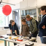 4 Personen stehen an einem Tisch mit technischen Geräten