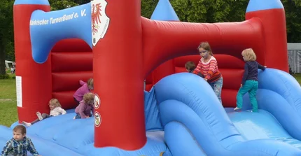 Mehrere Kinder spielen auf einer großen Hüpfburg.