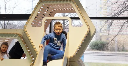 Kinder spielen auf einem Indoor-Spielplatz. Ein Junge sitzt auf der Rutsche.
