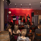 Vier Personen auf einer kleinen Bühne, davor sitzende Personen, die zuhören.