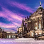 Die untergehende Sonne färbt den Himmel violett über den Communs am Neuen Palais.