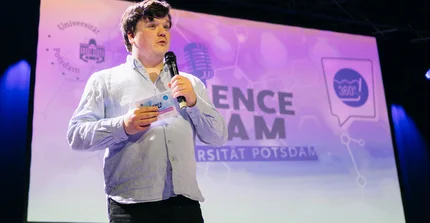Ein Teilnehmender des Science Slam auf der Bühne.