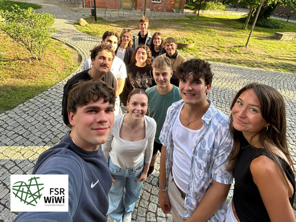 Gruppenfoto mit Gebäude und Wiese im Hintergrund