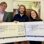 Professor Neitzel und die beiden Empfänger des Leistungsstipendiums mit den riesigen Checks