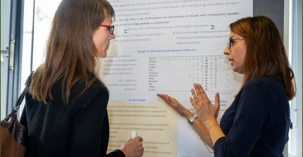 Auf dem Foto sind zwei Frauen an einer Tafel zu sehen. Eine erklärt der anderen eine Frage im Rahmen des Programms „Uni trifft Schule“. Das Bild hat Thomas Roese aufgenommen.