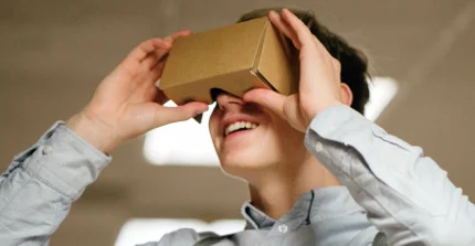 Ein Schüler blickt in eine Papphalterung für Virtual-Reality-Anwendungen auf dem Smartphone