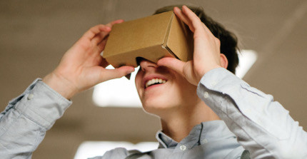 Ein Schüler blickt in eine Papphalterung für Virtual-Reality-Anwendungen auf dem Smartphone