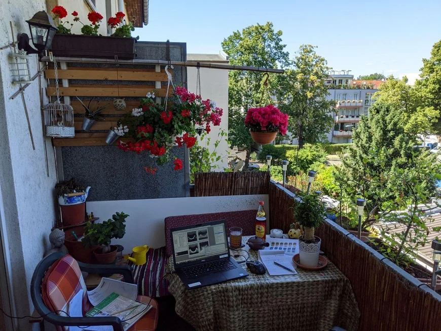 Ein Balkon mit Tisch und Stuhl. Laptop und Büchern. Blick ins Grüne