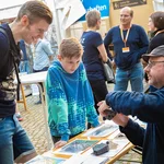 Eine Person zeigt zwei weiteren Personen etwas an einem Stein.