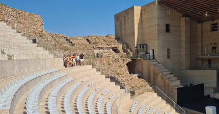 Ein Teil eines Amphittheaters ist modern bestuhlt. Der Rest zeigt archäologische Funde. Die moderne Bühne mit "Nicken" zur ursprünglichen historischen Herkunft ist ebenso zu erkennen.