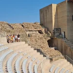 Ein Teil eines Amphittheaters ist modern bestuhlt. Der Rest zeigt archäologische Funde. Die moderne Bühne mit "Nicken" zur ursprünglichen historischen Herkunft ist ebenso zu erkennen.