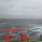 Paula standing on the helideck of the ship watching the stormy sea