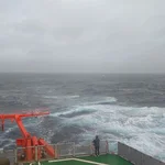 Paula standing on the helideck of the ship watching the stormy sea