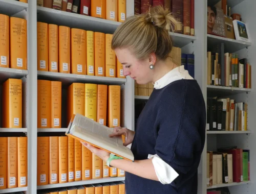 Studierende bei der Literaturrecherche vor einem Bücherregal
