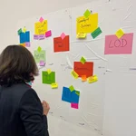 Participant of the DH Jewish Hackathon 2022 reads colorful Post-Its on the wall.