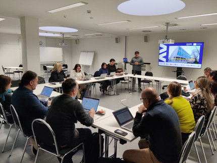 Projektarbeitsgruppe in einem Seminarraum an Tischen sitzend