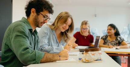 Vier junge Menschen sitzen an einem Tisch und sprechen