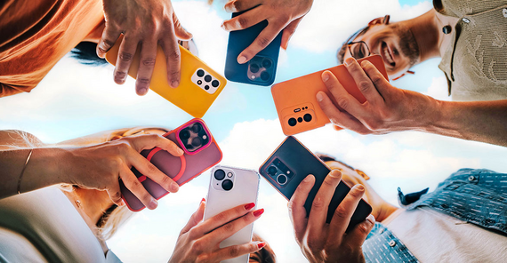 Aus der Froschperspektive: Junge Menschen stehen im Kreis und schauen auf ihr Smartphone