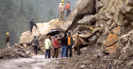 Menschen an von Steinen verschütteter Straße nach Lawine im Gebirge