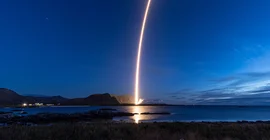 Illuminierter Raketenstart aus der Ferne am Nachthimmel.