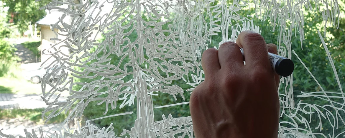 Hand mit einem Stift, die auf Glas malt - 