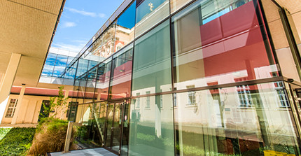 Modernes Glasfoyer einer Bibliothek, in dem Glas spiegeln sich alte Gebäude