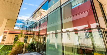 Modernes Glasfoyer einer Bibliothek, in dem Glas spiegeln sich alte Gebäude