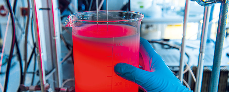 Reagenzglas mit rot leuchtender Flüssigkeit in einer Laborumgebung