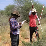 Zwei Forschende führen wissenschaftliche Messungen in der afrikanischen Savanne durch