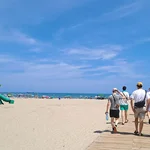 Strandszene in Weitwinkelaufnahme: Studierende, die von der Kamera weg gen Meer laufen.