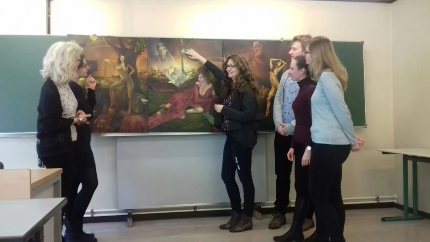 Studierende und Lehrende vor einer Tafel, auf der ein Gemälde gezeigt wird