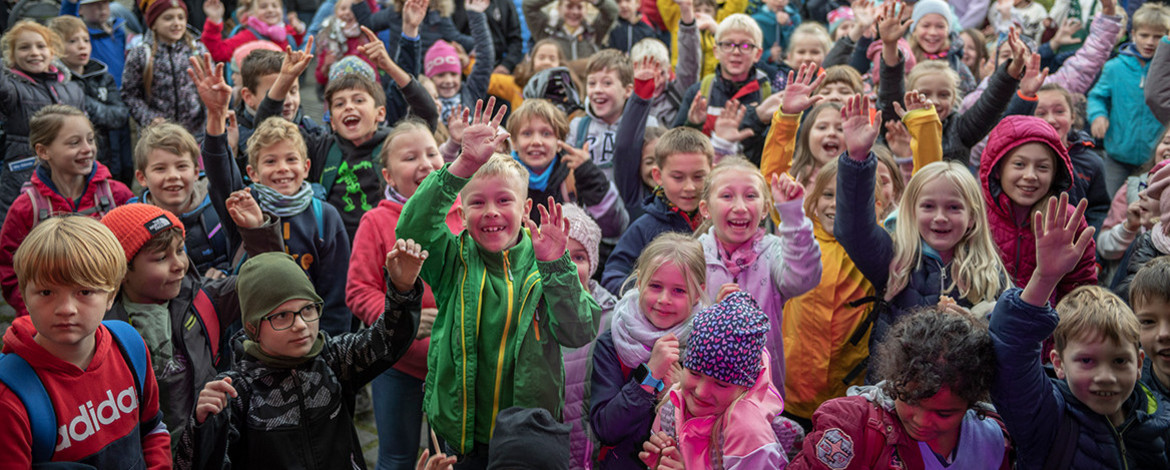 Eine große Gruppe Kinder jubelt vor einer Bühne - 