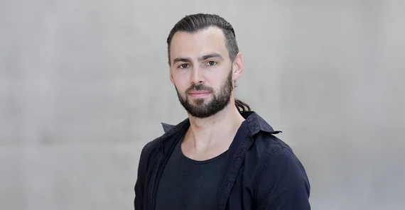 Steffen Hagemann in a portrait in front of a grey concrete wall on the Griebnitzsee campus.