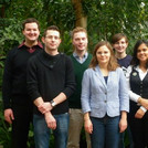 Kulak group in front of plants in a botanical garden