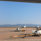 Flughafen von Castellón mit Flugzeugen und Flughafenfahrzeugen im Vorder- und Mittelgrund. Im Hintergrund Berge und darüber wolkenloser Himmel.