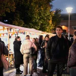 Mehrere Personen vor erleuchteten Marktständen