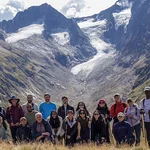Eine Gruppe von Menschen posiert vor hohen Bergen im Hintergrund für ein Gruppenfoto
