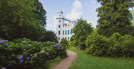 Ein Gebäude auf der Pfaueninsel malerisch eingerahmt von Parkanlage.