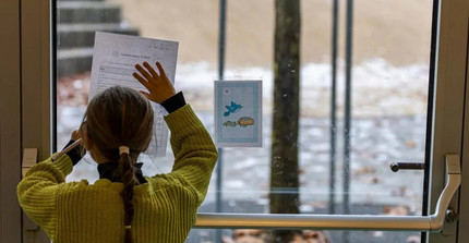 Schülerin bearbeitet Arbeitsblatt an einer Fensterscheibe