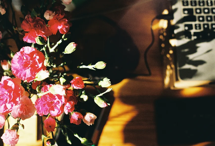 links scharf im bild ein strauß blumen und rechts im hintergrund eher unschaft im anschnitt die tastatur eines laptops