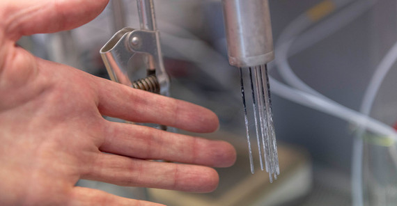 The researchers take a test measurement with the probe. The immersed rods serve as laser sources in the visible and near infrared spectral range to generate photon density waves in the light-scattering solution.