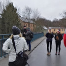Teilnehmer stehen auf einer Brücke und lauschen dem Wissenschaftler