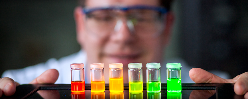 Farbige Reagenzgläser stehen in Reihe in einem Labor.