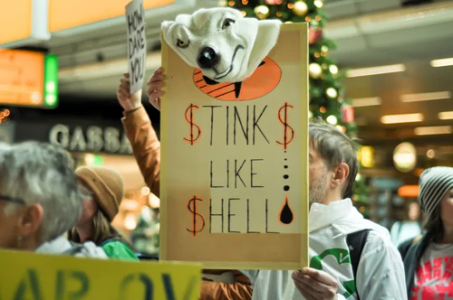 A protester holds a sign with the inscription 'stinks like Shell"