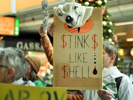 A protester holds a sign with the inscription 'stinks like Shell"
