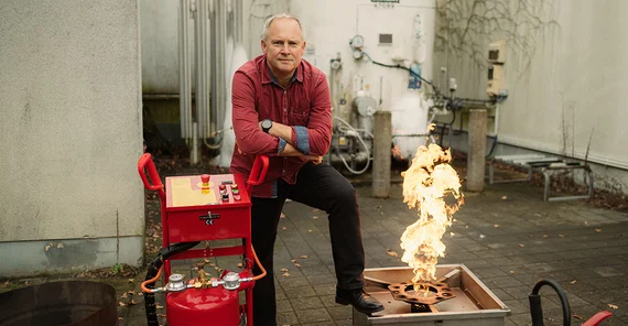Ulf Lepszy is posing next to an open flame and a fire extinguisher.