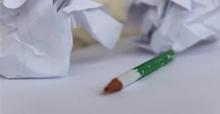 zerknülltes Papier und abgegriffener Bleistift ohne Spitze auf einem Tisch; Foto: G., Strecker