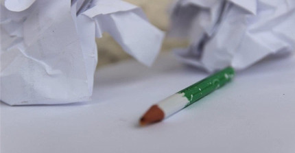 zerknülltes Papier und abgegriffener Bleistift ohne Spitze auf einem Tisch; Foto: G., Strecker