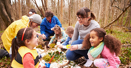 Lehrer mit Kindern im Herbstwald beim Unterricht