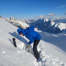 Field site Zugspitze: Scientist digging a snow pit at a steep hillslope with white mountains in the background | Photo: Cosmic Sense Consortium